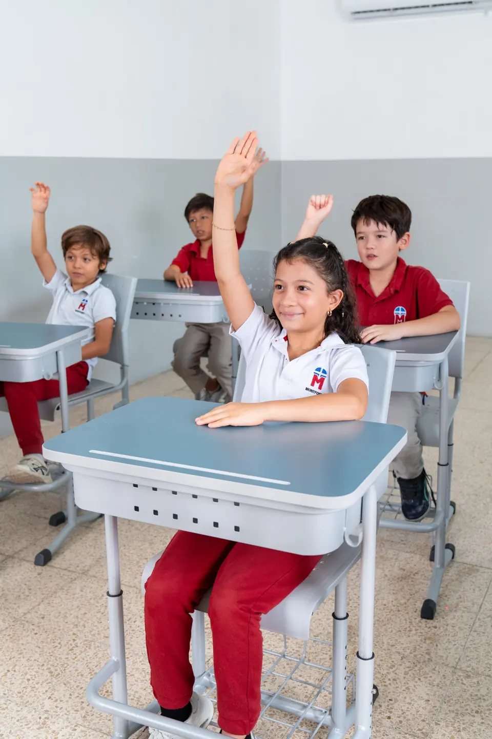 Estudiantes de primaria Montfort levantando la mano en clase