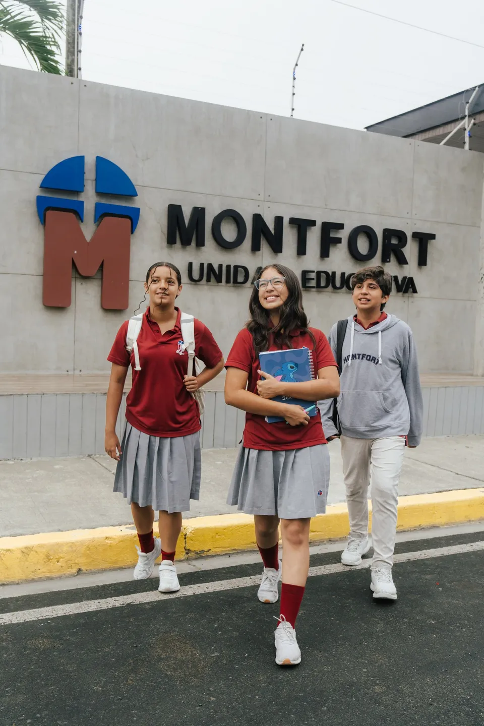 Estudiantes de bachillerato saliendo junto al logo del colegio